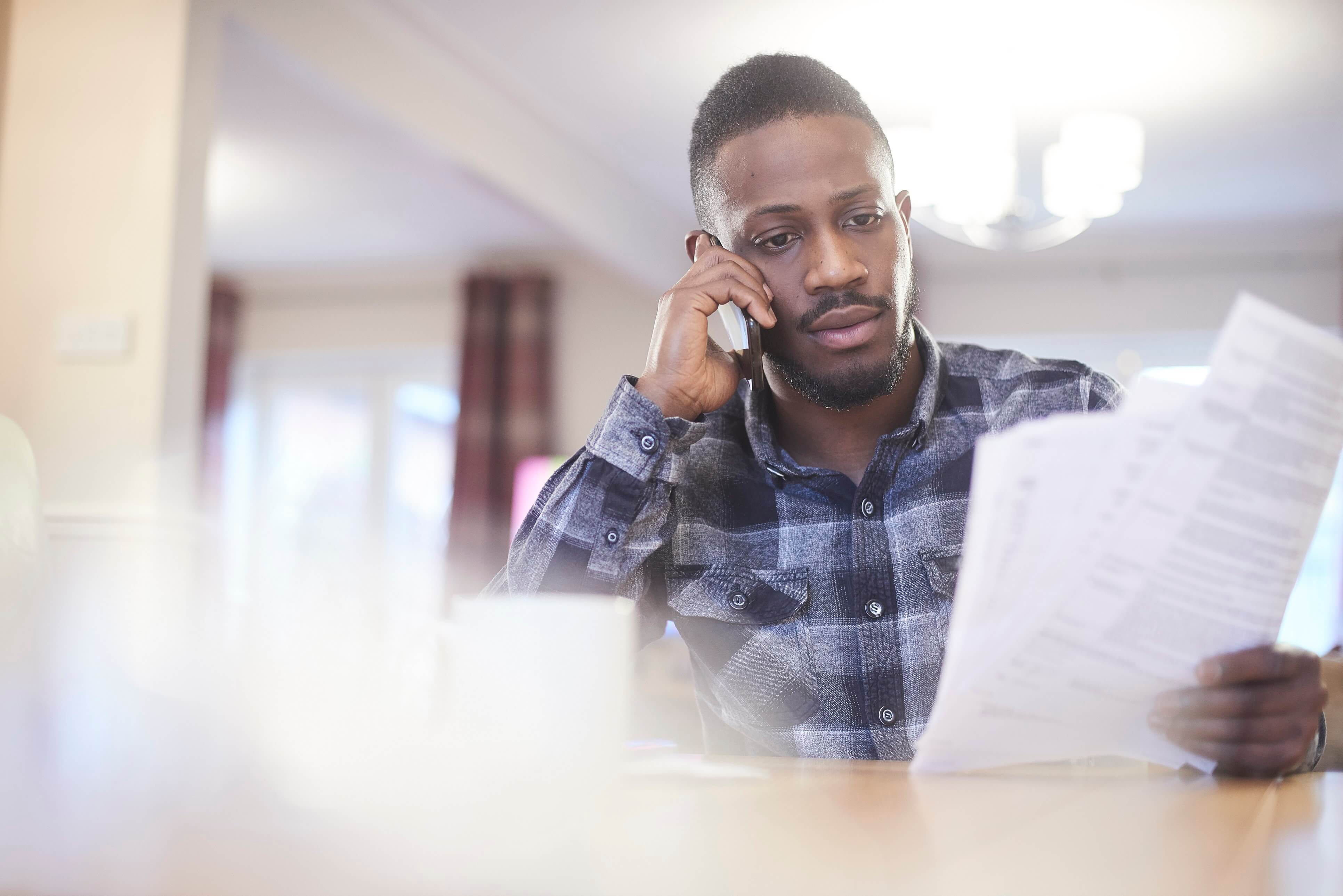 Concerned Man On the Phone Whilst Holding Documents